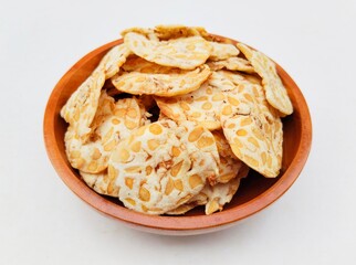 Tempeh chips in a wooden bowl on a white background. High angle view. 