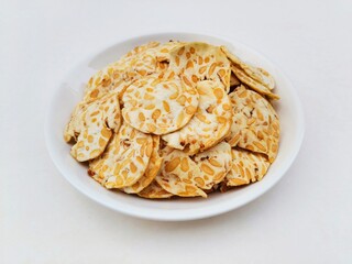 Tempeh chips in a white plate on a white background.