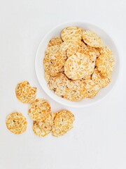 Tempeh chips in a white plate on a white background. Top of view. 