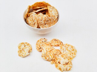 Tempeh chips in a white bowl on a white background.