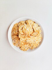 Tempeh chips in a white plate on a white background. Top of view. 
