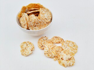 Tempeh chips in a white bowl on a white background.