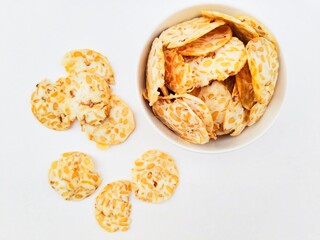 Tempeh chips in a white bowl on a white background. Top of view. 