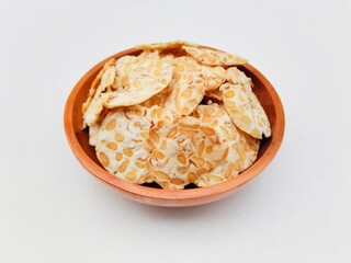 Tempeh chips in a wooden bowl on a white background. High angle view. 
