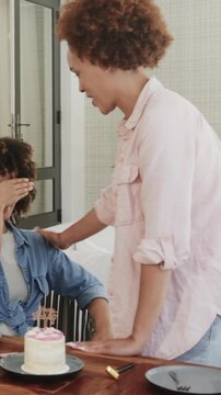 Vertical video: Diverse female friends bringing surprise to table crowning feeding cake and hugging