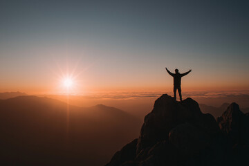 Transform your life, unlock your potential, and claim the power within. Man hiking to the top of mountain to see the sunrise. Achievement and accomplishment feelings.