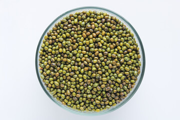 Top view of a clear glass bowl filled with green mung beans, isolated on a clean white background.