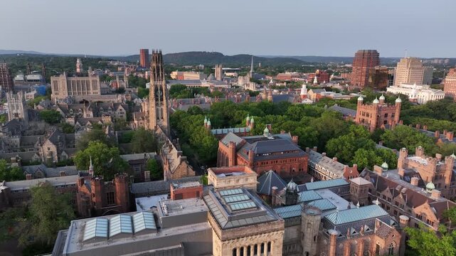 Historic town of New Haven in Connecticut, USA. golden sunset time in summer. Descend drone wide shot. Gothic Yale university and tower buildings in center. Downtown complex in distance. Brick gothic.