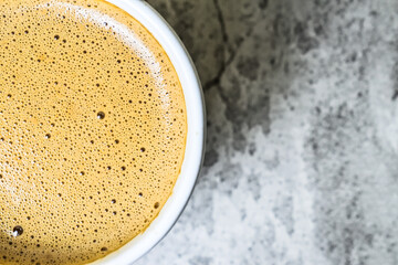 Top view of hot cappucino in the ceramic mug or glass. high angle, above, extreme close up. half. copy space, empty, free, negative, design, text. grey or gray cement as background.