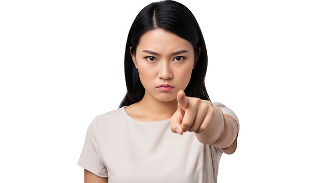 Portrait of a serious and angry Asian woman pointing her finger forward with an accusatory gesture isolated on a white studio background.