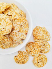 Close-up of tempeh chips in a white plate on a white background. 