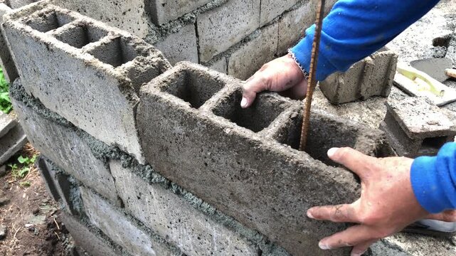 concrete mason is laying hollow blocks for an outdoor bathing facility on the farm. Close up
