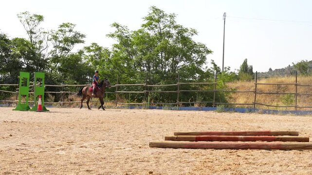 Two riders guide their mounts between three ground bars as part of competition practice