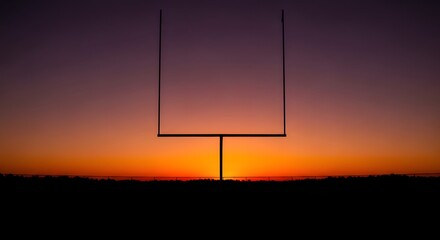 A striking silhouette of a football goalpost against a vibrant sunset sky, creating a dramatic scene.