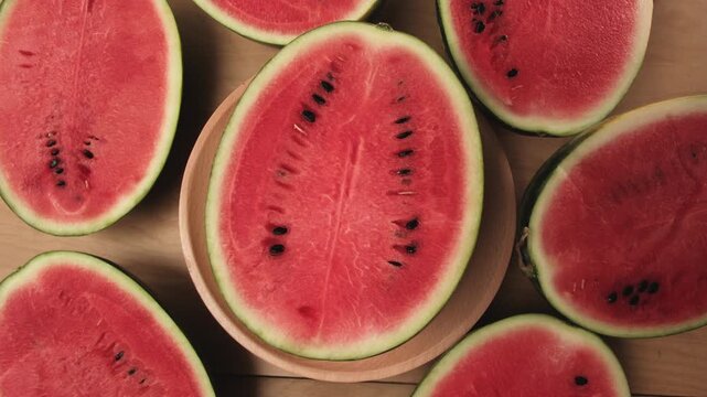 Close-up shot of half pieces of fresh red watermelons on a wooden dish, natural texture background pattern with tropical sweet and nutritious snack in hot summertime, healthy food with abundant fruit.