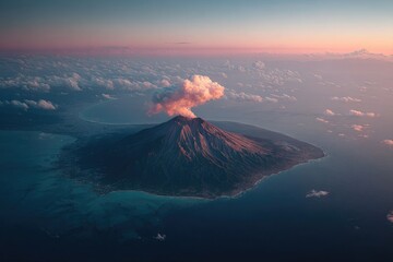 Aerial view of active volcano erupting, surrounded by clouds and water