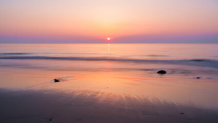 Obraz premium Serene ocean sunset with soft pastel colors reflecting on wet sand and gentle waves creating a peaceful and tranquil atmosphere for relaxation and contemplation