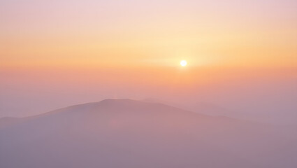 Obraz premium Serene sunrise over a misty mountain landscape with soft pastel colors creating a tranquil and atmospheric scene