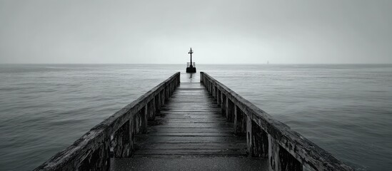 Gray, moody pier extending into a vast, tranquil sea
