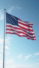 Obraz premium American flag waving against a clear blue sky on a sunny day with a tall silver flagpole