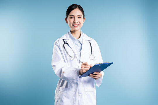 Friendly doctor with stethoscope writing on blue clipboard in light blue backdrop Healthcare