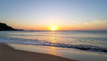 Obraz premium Serene beach scene at sunset with golden sky and calm ocean waves gently washing onto the sandy shore, scenic coastal landscape du twilight hours