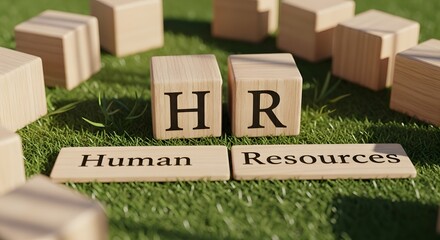 Wooden blocks spelling "HR" and "Human Resources" on a green grassy surface, symbolizing business concepts.