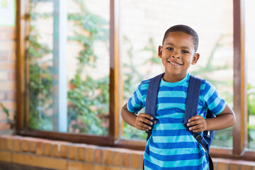 Child standing on brick windowsill by window gripping backpack and admiring climbing plants