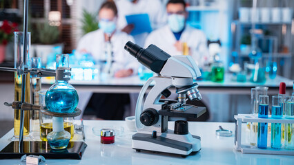 A group of young scientists are conducting experiments in the lab using a microscope., Aspiring scientists are busy running laboratory experiments