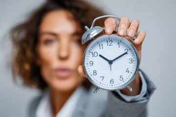Concept of time management with a focused businesswoman holding clock