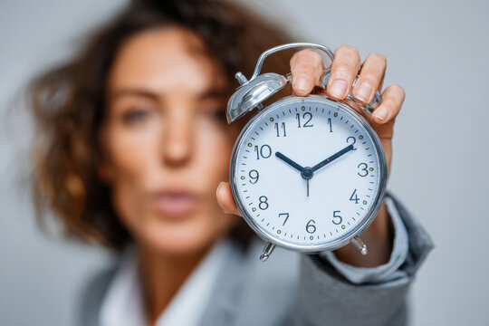 Concept of time management with a focused businesswoman holding clock