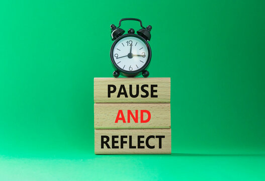 Pause and Reflect symbol. Concept words Pause and Reflect on wooden blocks. Beautiful green background with alarm clock. Business and Pause and Reflect concept. Copy space.