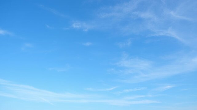 A timelapse of this blue sky captures delicate wisps of white clouds drifting across a bright expanse, symbolizing fair weather, calm conditions, and the gentle flow of atmospheric patterns in motion.