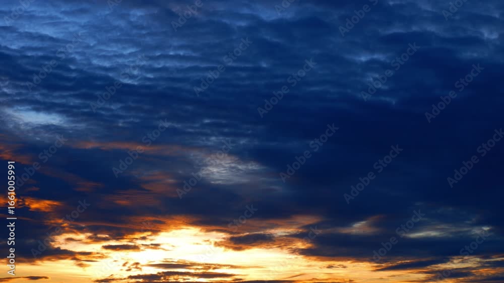 Wall mural a sunrise time-lapse reveals golden light breaking through dense, dark clouds, casting fiery tones a
