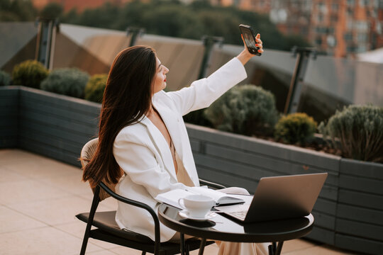 Young woman enjoying the sunset while taking a selfie on a rooftop terrace
