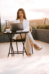 Fototapeta premium Young professional working outdoors at sunset while enjoying coffee