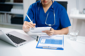 Doctor or nurse working on laptop to manage digital health records and patient information. Real people in medical office