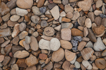 A top-down, detailed texture of smooth, multi-colored river stones and pebbles, creating a natural and abstract background.