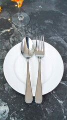 Empty white plate with spoon and fork on gray marble