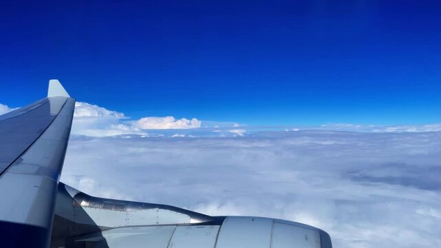 an airplane flys over the clouds, port side view through the window,