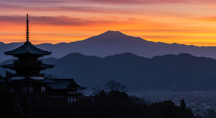 A serene sunset over a mountain range with a Japanese temple in the foreground.