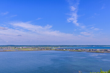 Scenic summer landscape from Cape Azechi in Hamanaka Town, Hokkaido, Japan. The viewpoint offers a wide view of Hamanaka Town, Kenbotsukito Island, small islets, and the Pacific Ocean under a clear bl