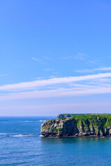 Scenic summer landscape from Cape Azechi in Hamanaka Town, Hokkaido, Japan. The viewpoint offers a wide view of Hamanaka Town, Kenbotsukito Island, small islets, and the Pacific Ocean under a clear bl