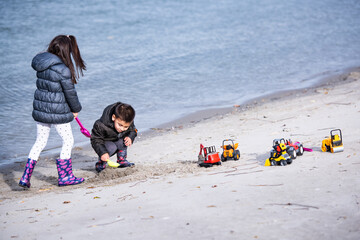 Children playing with toy trucks and shovels on beach