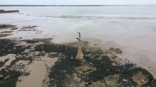 Approaching drone movement to the iconic American monument aka Le Sammy in shallow water during low tide, Saint-Nazaire, Loire-Atlantique, France.