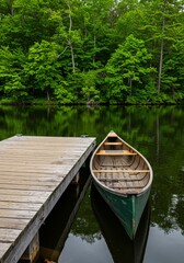Obraz premium Green Wooden Canoe Moored at a Wooden Dock on a Calm Lake Surrounded by Lush Green Trees
