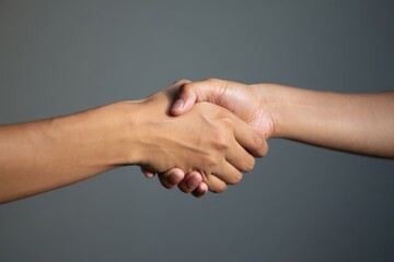 A closeup shot of two hands shaking against a gray background with soft lighting effect