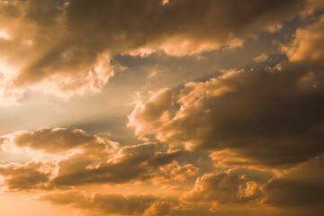 Obraz premium Dramatic golden hour sunlight illuminates stormy cumulus clouds creating a powerful and awe inspiring skyscape