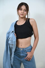 young woman in thinking pose. hands and body sing and symbol. close hands. fingers touch the face. jeans and white wall. beauty and fashion