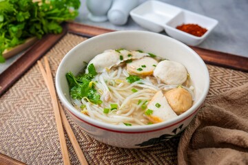 Clear noodle soup with thin rice noodles in ceramic bowl with chopsticks
